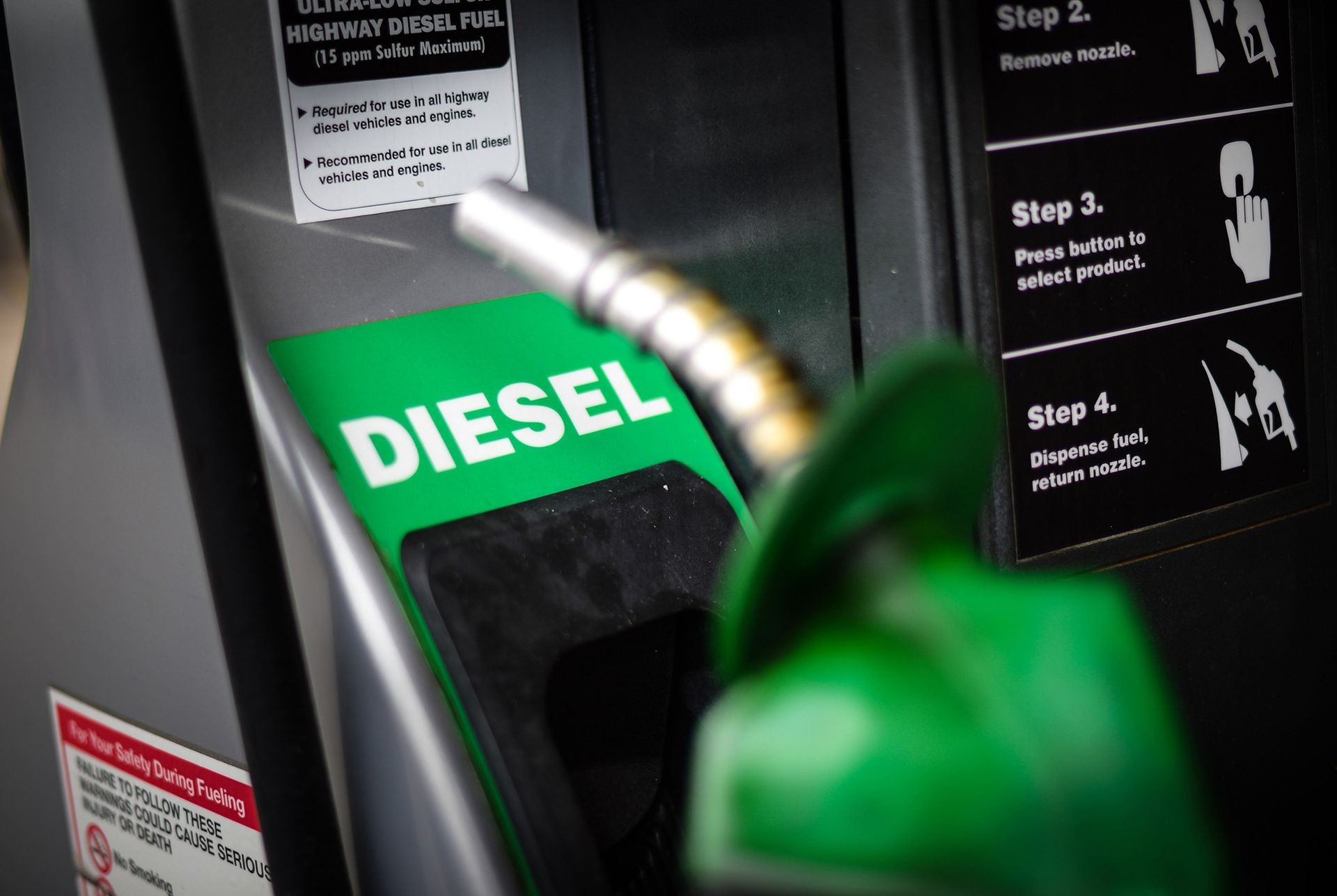 Close-up of a diesel fuel pump with green nozzle and instructions for fueling on the right side.